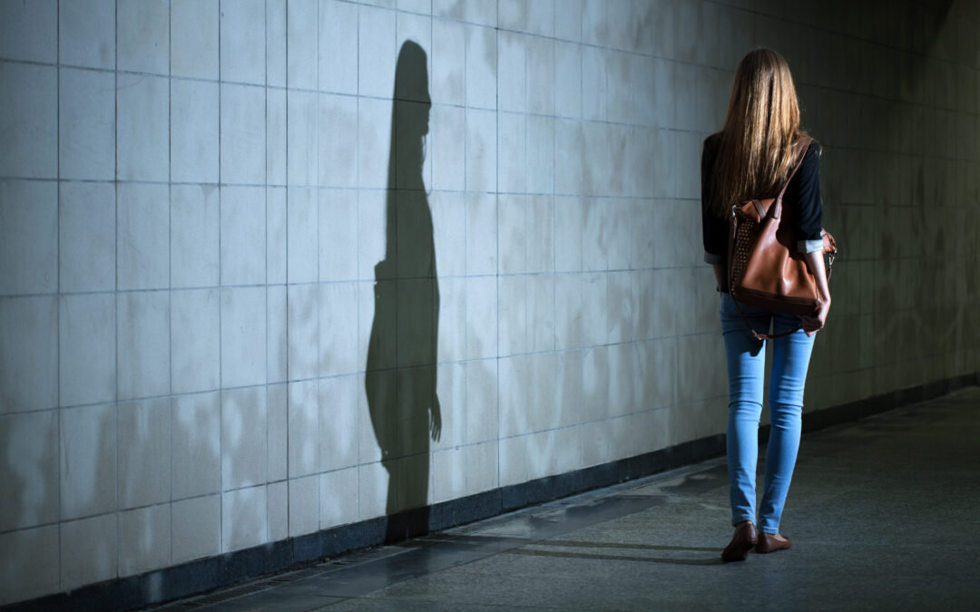 woman walking alone, her shadow is seen on the wall